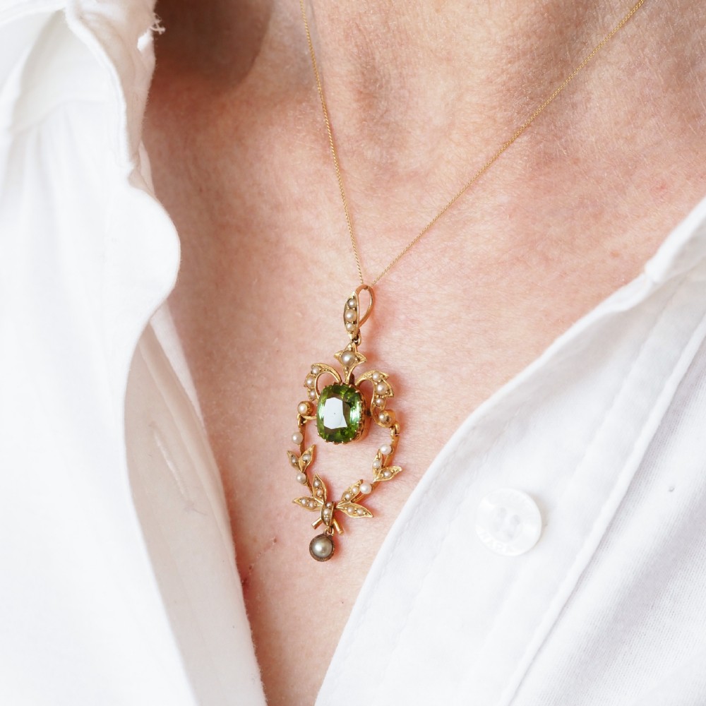 A late Victorian 14-carat yellow gold openwork pendant featuring a cushion-cut green peridot encircled by seed pearl foliate scrolls and a dangling pearl drop. View IX