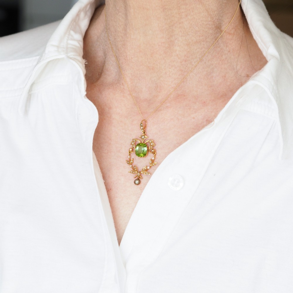 A late Victorian 14-carat yellow gold openwork pendant featuring a cushion-cut green peridot encircled by seed pearl foliate scrolls and a dangling pearl drop. View XI