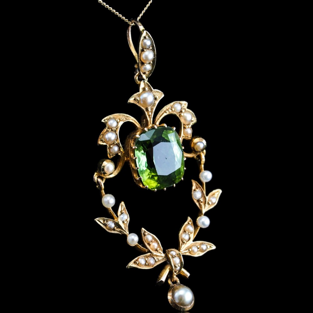 A late Victorian 14-carat yellow gold openwork pendant featuring a cushion-cut green peridot encircled by seed pearl foliate scrolls and a dangling pearl drop. View XVI