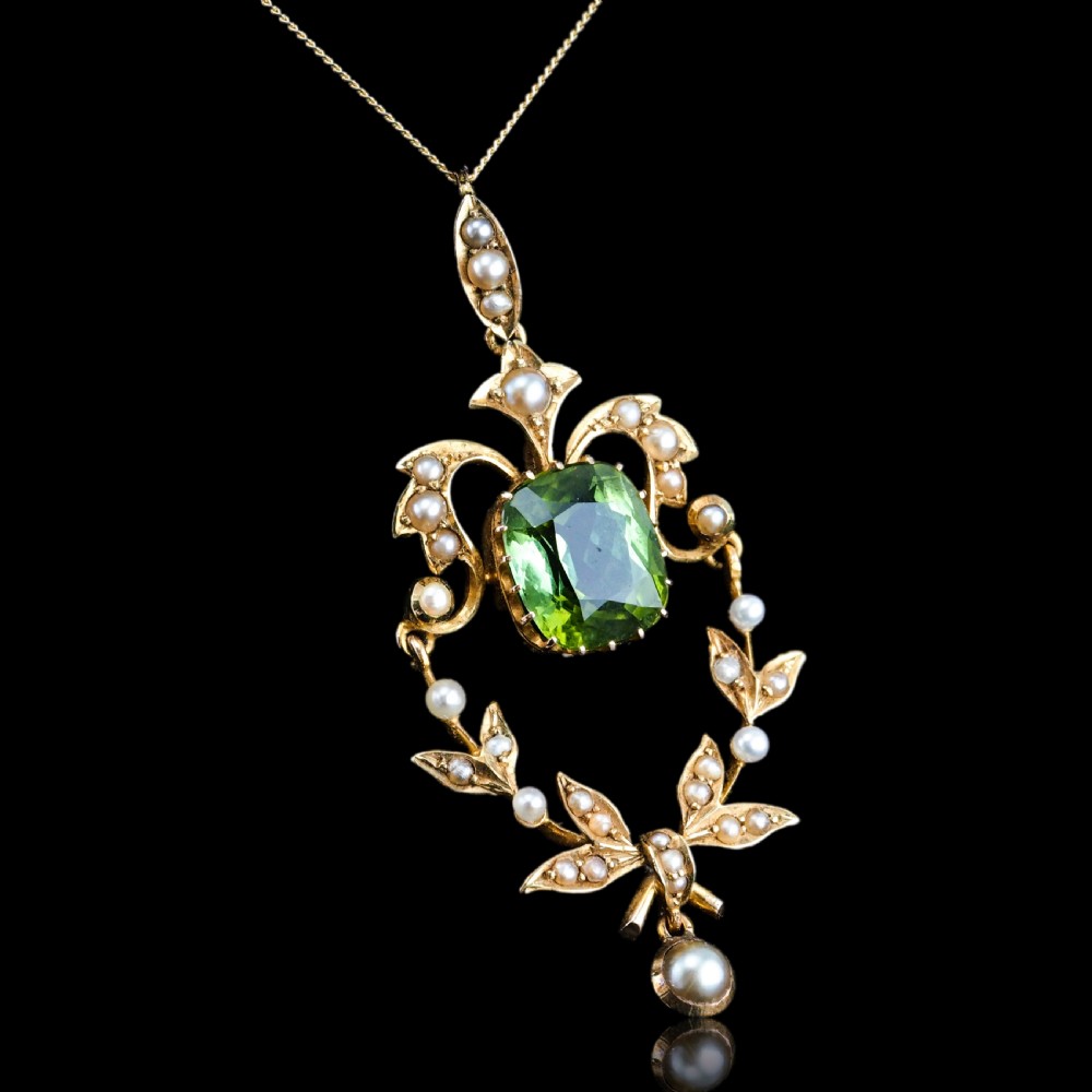 A late Victorian 14-carat yellow gold openwork pendant featuring a cushion-cut green peridot encircled by seed pearl foliate scrolls and a dangling pearl drop. View XVII