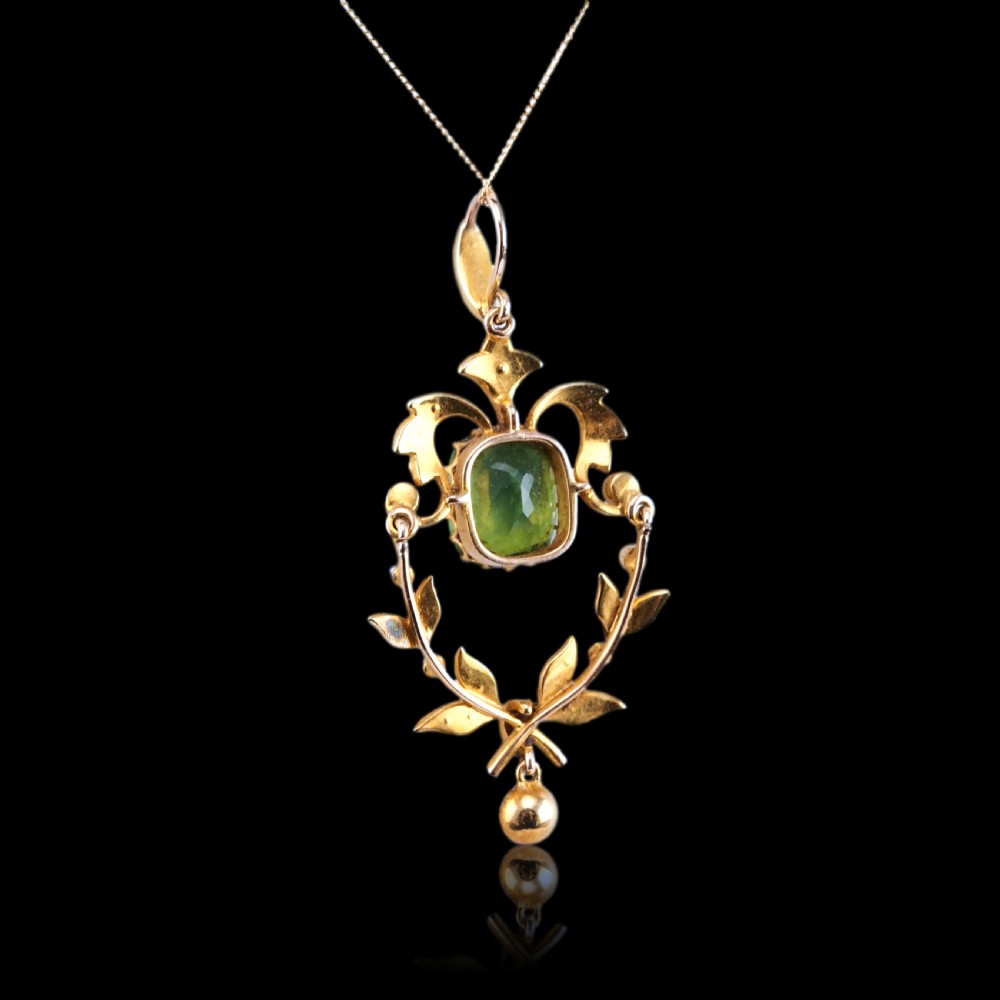A late Victorian 14-carat yellow gold openwork pendant featuring a cushion-cut green peridot encircled by seed pearl foliate scrolls and a dangling pearl drop. View XXII
