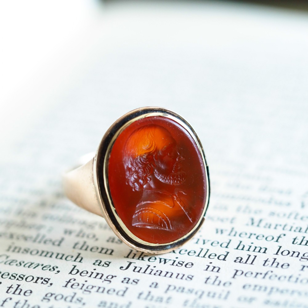 An antique gold signet ring featuring an oval red carnelian gemstone carved with the side profile portrait of a gentleman. View V