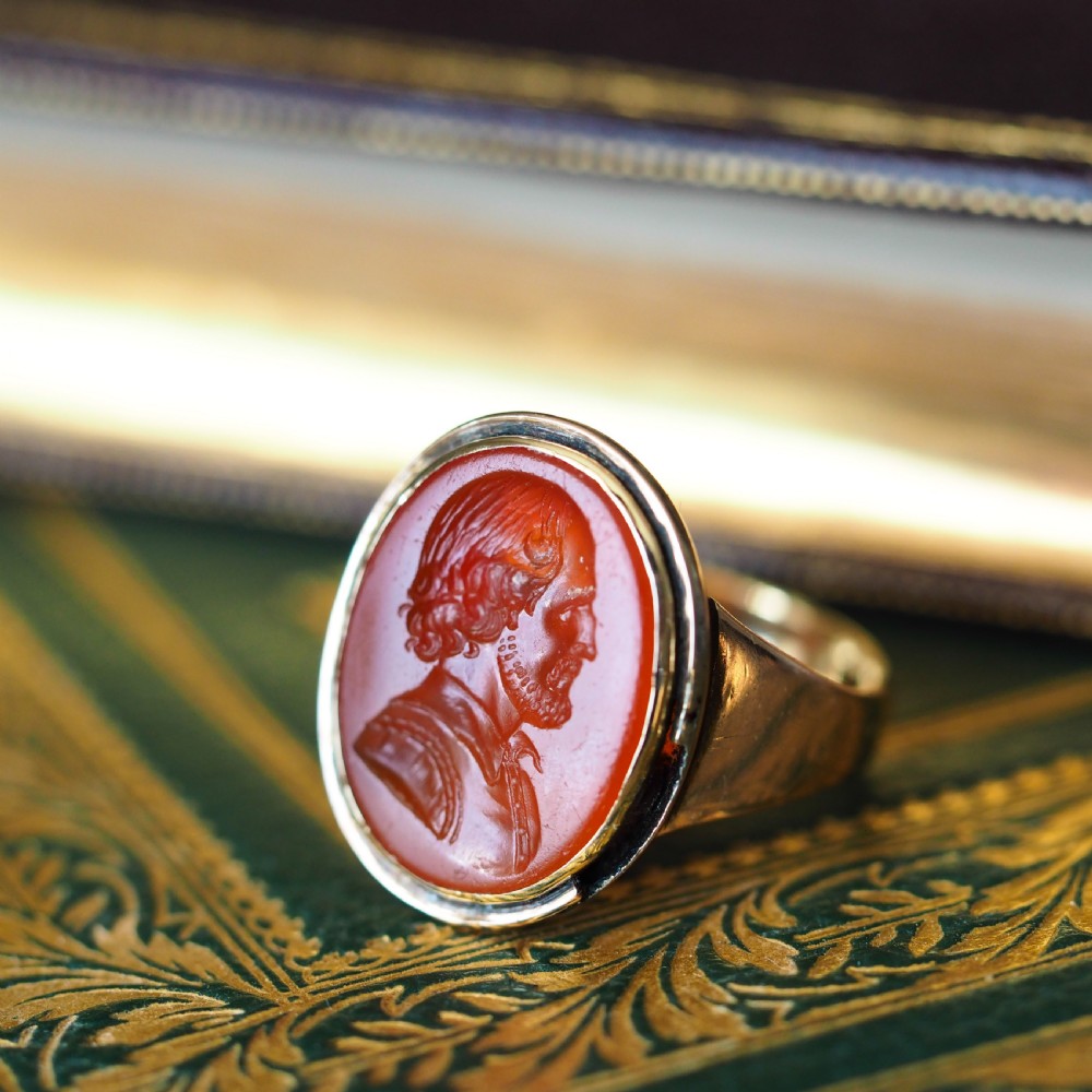 An antique gold signet ring featuring an oval red carnelian gemstone carved with the side profile portrait of a gentleman. View VII