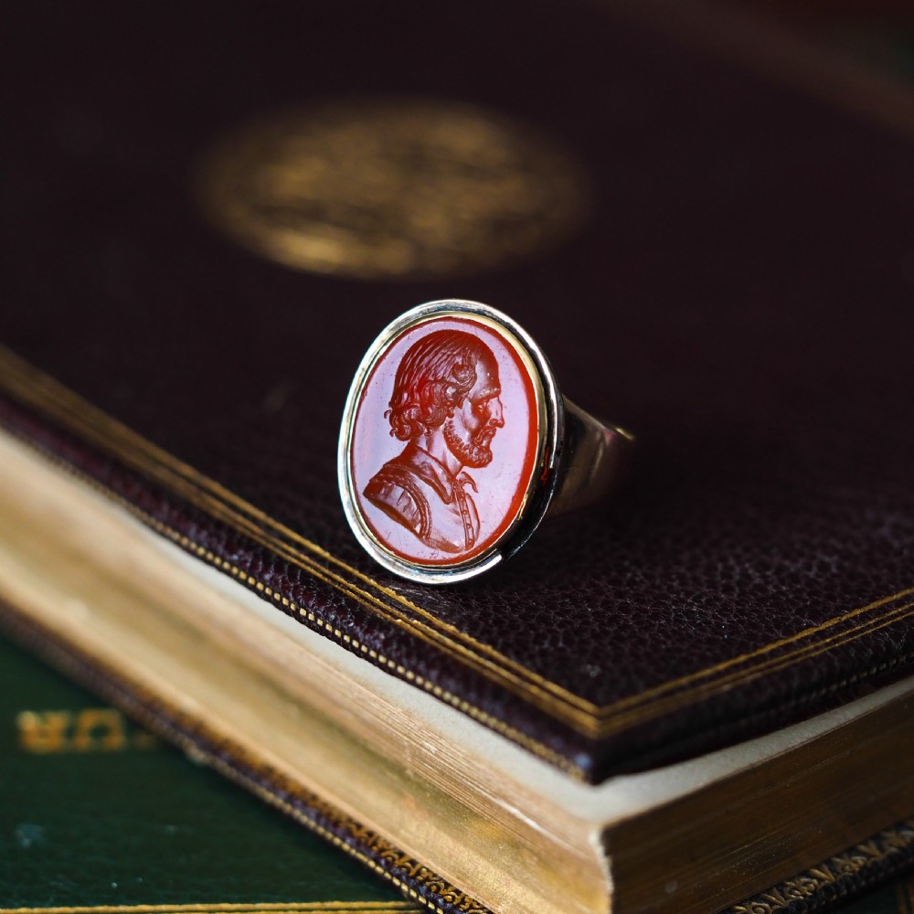 An antique gold signet ring featuring an oval red carnelian gemstone carved with the side profile portrait of a gentleman. View X