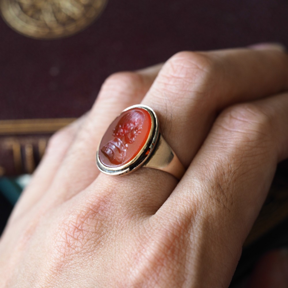 An antique gold signet ring featuring an oval red carnelian gemstone carved with the side profile portrait of a gentleman. View XIII