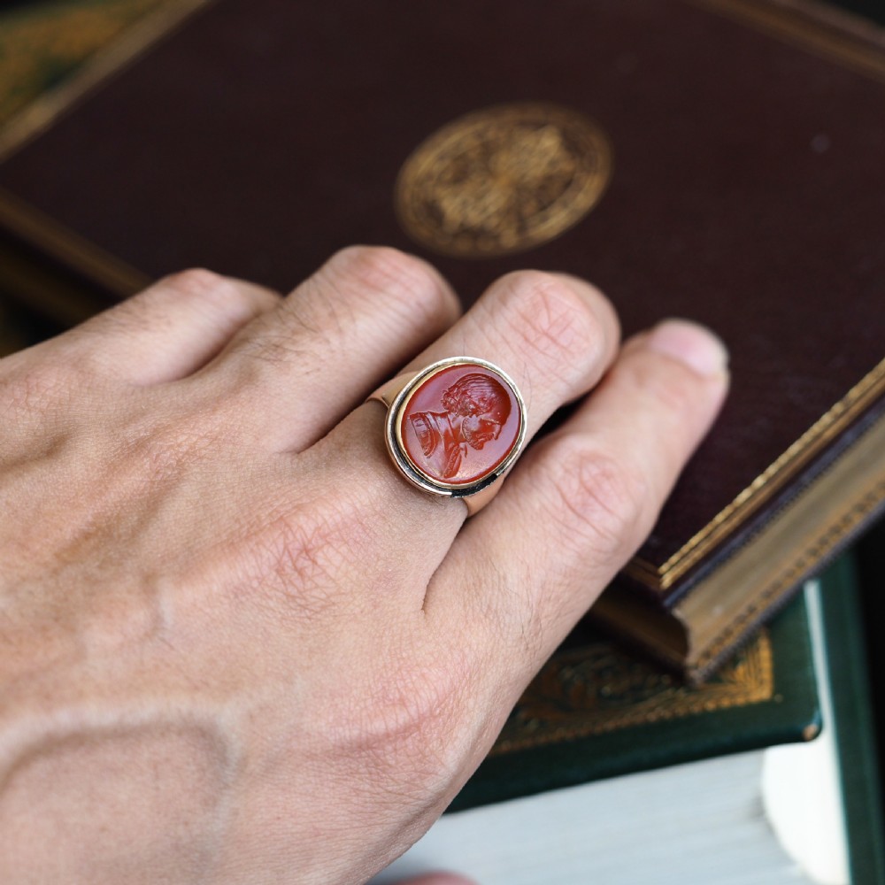 An antique gold signet ring featuring an oval red carnelian gemstone carved with the side profile portrait of a gentleman. View XIV