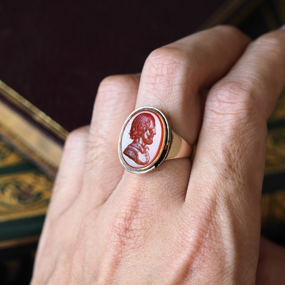 An antique gold signet ring featuring an oval red carnelian gemstone carved with the side profile portrait of a gentleman. View XV