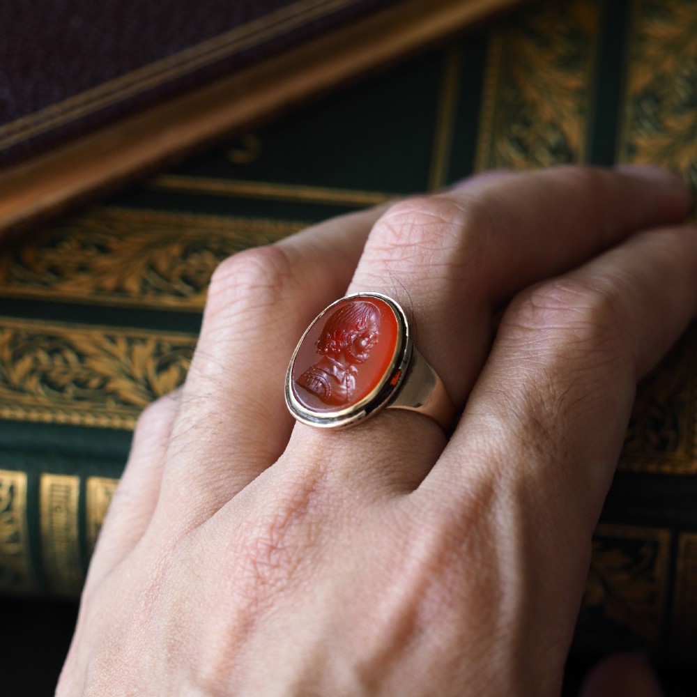 An antique gold signet ring featuring an oval red carnelian gemstone carved with the side profile portrait of a gentleman. View XVI