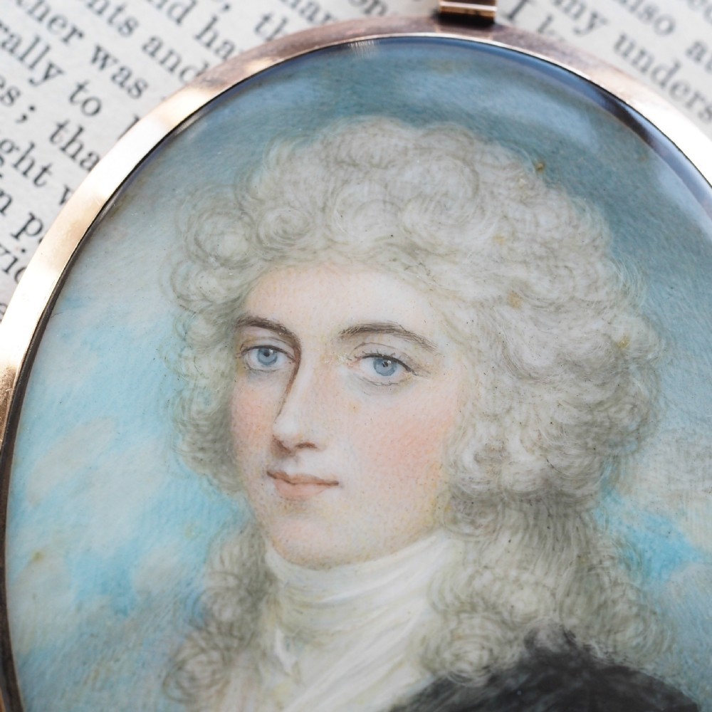 An oval Georgian portrait miniature depicting a subject with light powdered hair set in a 14k gold frame with a top bail. View VII