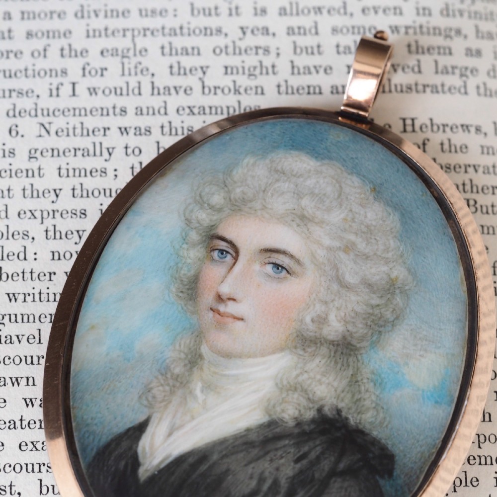 An oval Georgian portrait miniature depicting a subject with light powdered hair set in a 14k gold frame with a top bail. View VIII