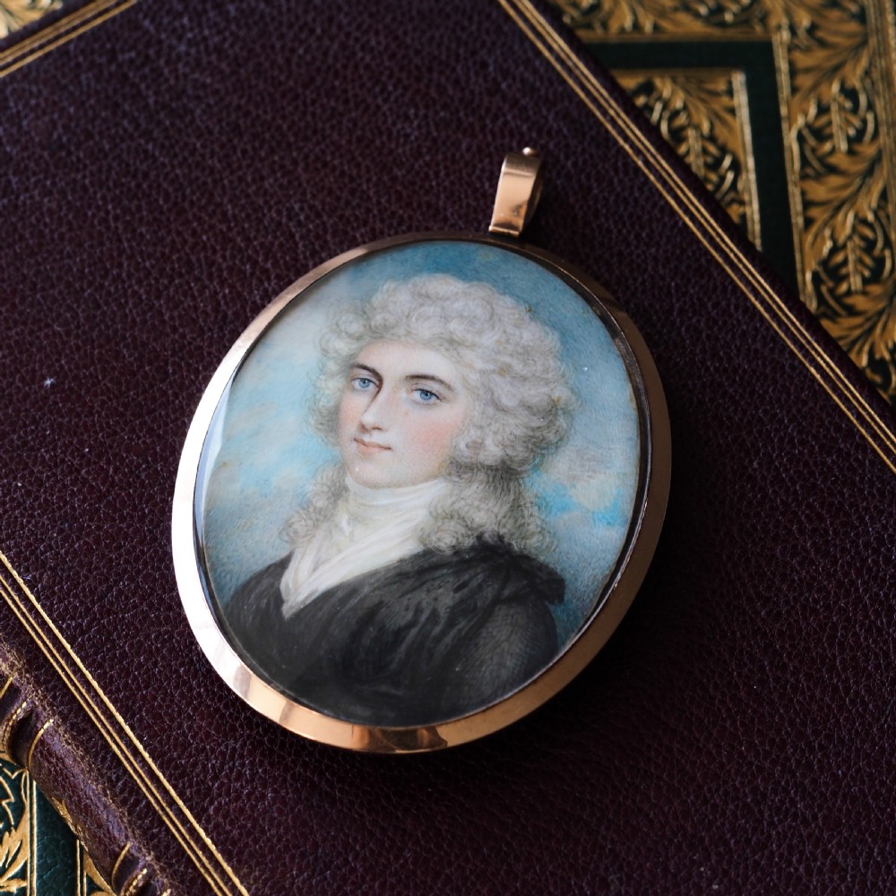 An oval Georgian portrait miniature depicting a subject with light powdered hair set in a 14k gold frame with a top bail. View XIII