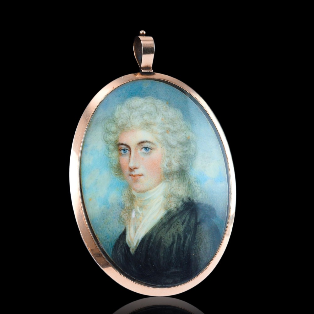 An oval Georgian portrait miniature depicting a subject with light powdered hair set in a 14k gold frame with a top bail. View XV
