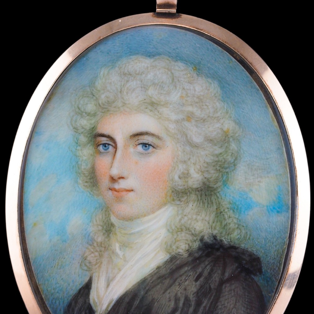 An oval Georgian portrait miniature depicting a subject with light powdered hair set in a 14k gold frame with a top bail. View XVI