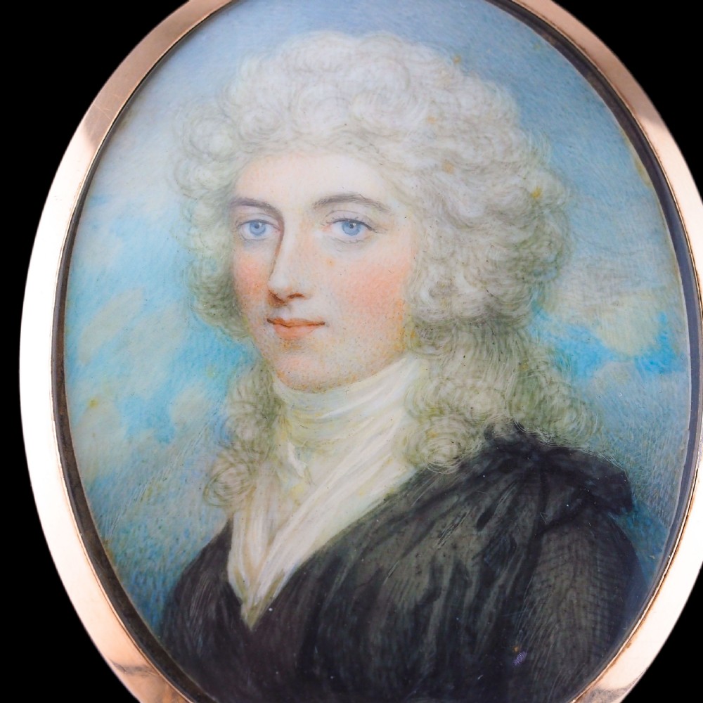 An oval Georgian portrait miniature depicting a subject with light powdered hair set in a 14k gold frame with a top bail. View XVII
