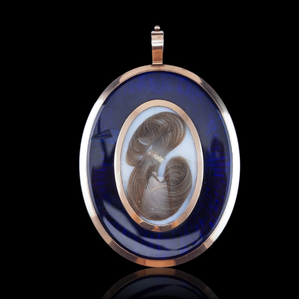 An oval Georgian portrait miniature depicting a subject with light powdered hair set in a 14k gold frame with a top bail. View XIX