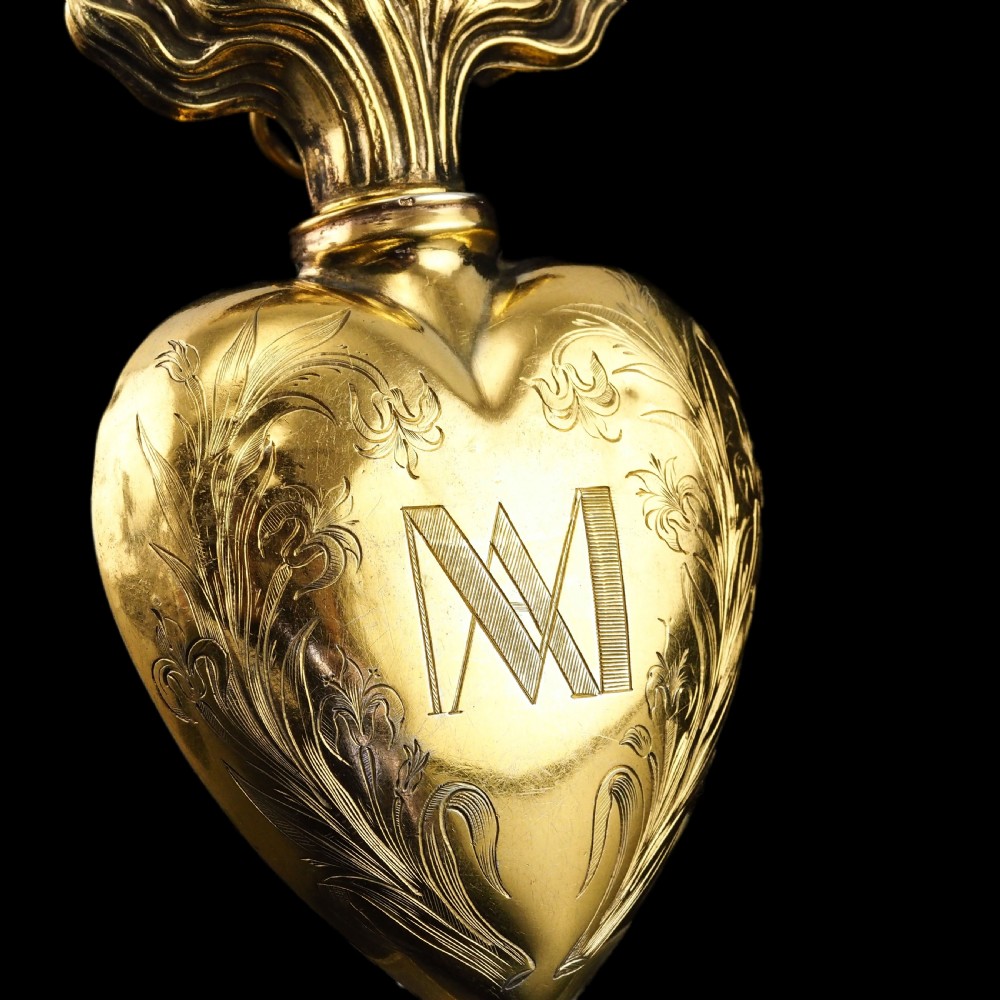 A 19th-century French silver-gilt heart-shaped scent bottle featuring an engraved monogram, foliate scrollwork, and a flame-shaped stopper. View II