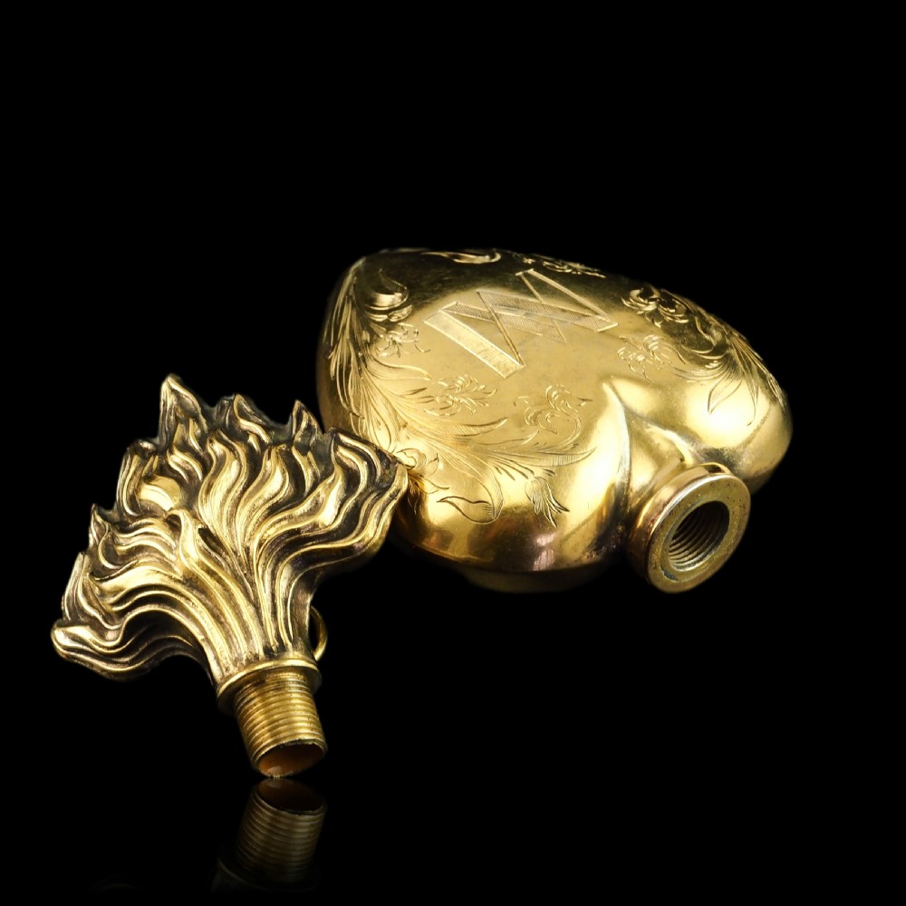 A 19th-century French silver-gilt heart-shaped scent bottle featuring an engraved monogram, foliate scrollwork, and a flame-shaped stopper. View XVIII