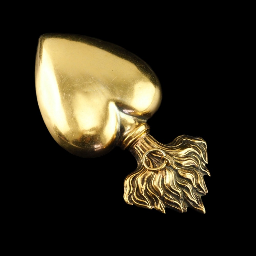 A 19th-century French silver-gilt heart-shaped scent bottle featuring an engraved monogram, foliate scrollwork, and a flame-shaped stopper. View XIX