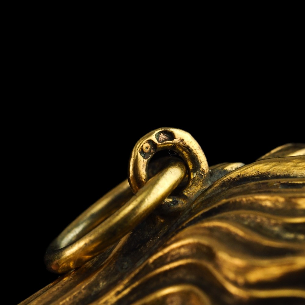 A 19th-century French silver-gilt heart-shaped scent bottle featuring an engraved monogram, foliate scrollwork, and a flame-shaped stopper. View XXI