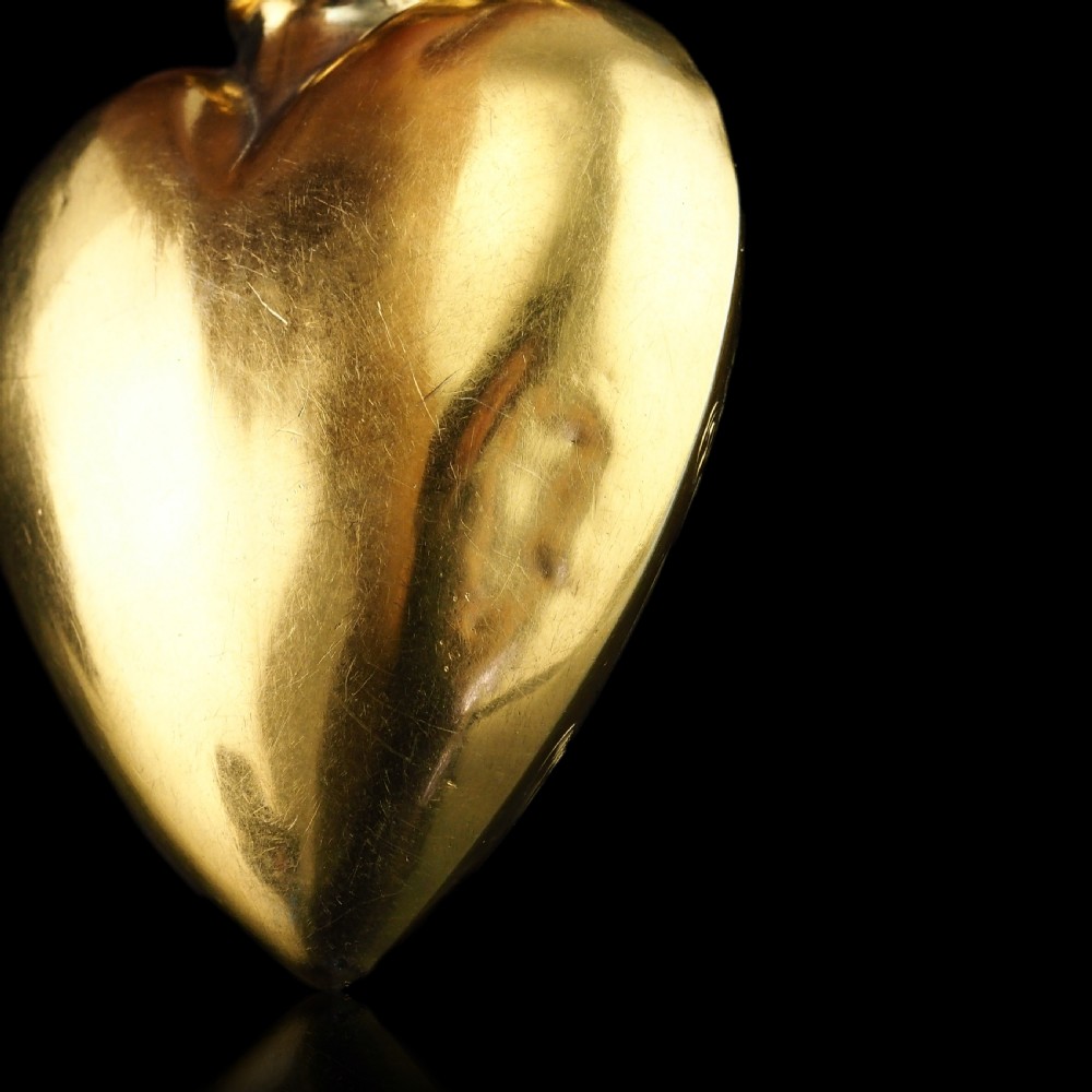 A 19th-century French silver-gilt heart-shaped scent bottle featuring an engraved monogram, foliate scrollwork, and a flame-shaped stopper. View XXII