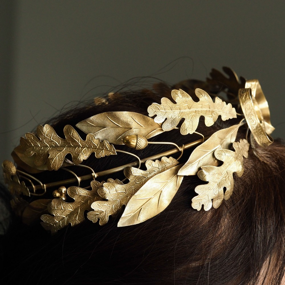 A 19th-century silver gilt foliate crown featuring detailed oak leaves, acorns, laurel leaves, and a central ribbon bow medallion. View V