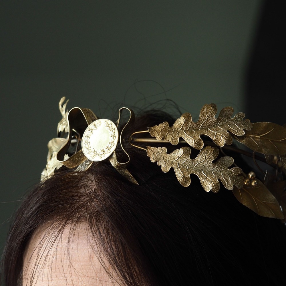 A 19th-century silver gilt foliate crown featuring detailed oak leaves, acorns, laurel leaves, and a central ribbon bow medallion. View VII