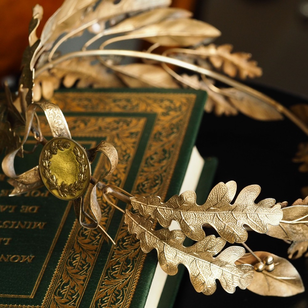 A 19th-century silver gilt foliate crown featuring detailed oak leaves, acorns, laurel leaves, and a central ribbon bow medallion. View VIII