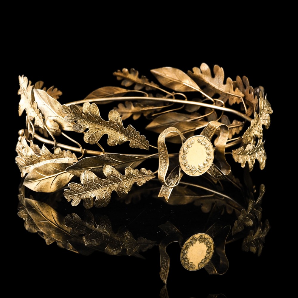 A 19th-century silver gilt foliate crown featuring detailed oak leaves, acorns, laurel leaves, and a central ribbon bow medallion. View XII