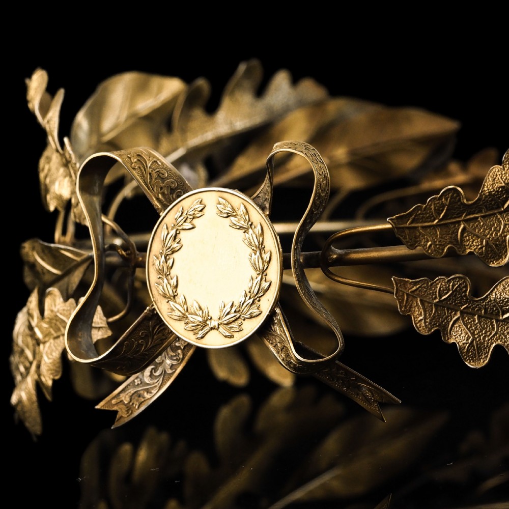 A 19th-century silver gilt foliate crown featuring detailed oak leaves, acorns, laurel leaves, and a central ribbon bow medallion. View XV