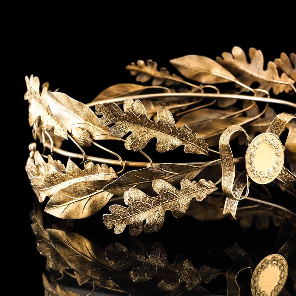 A 19th-century silver gilt foliate crown featuring detailed oak leaves, acorns, laurel leaves, and a central ribbon bow medallion. View XVII