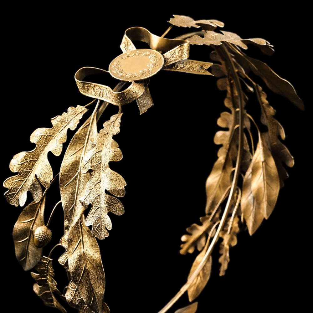 A 19th-century silver gilt foliate crown featuring detailed oak leaves, acorns, laurel leaves, and a central ribbon bow medallion. View XVIII