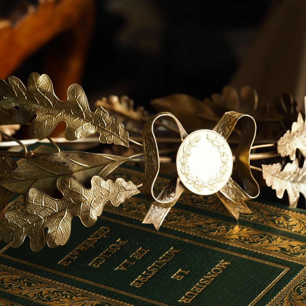 A 19th-century silver gilt foliate crown featuring detailed oak leaves, acorns, laurel leaves, and a central ribbon bow medallion. View XXIII