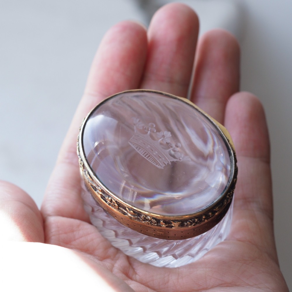 An oval cut crystal box featuring a gilt silver rim and a transparent glass lid etched with a nobility coronet crest. View VIII