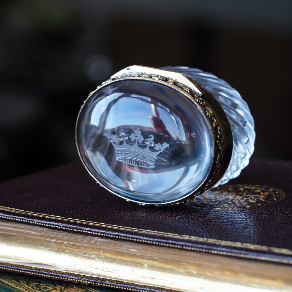 An oval cut crystal box featuring a gilt silver rim and a transparent glass lid etched with a nobility coronet crest. View XIV
