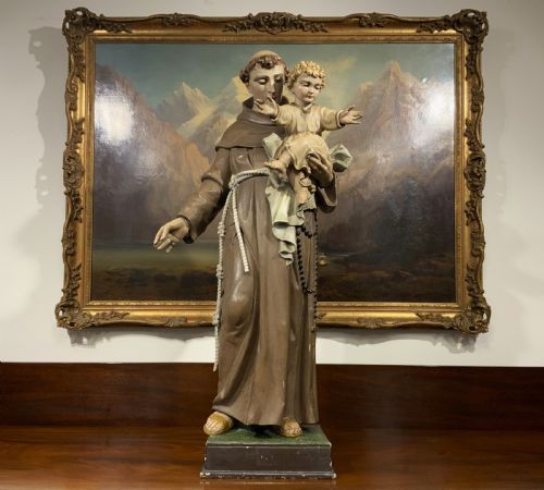 fig 1. A carved polychrome wood statue depicting a saint in a brown robe holding the infant Jesus.