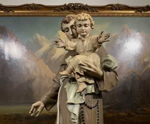 fig 4. A carved polychrome wood statue depicting a saint in a brown robe holding the infant Jesus.