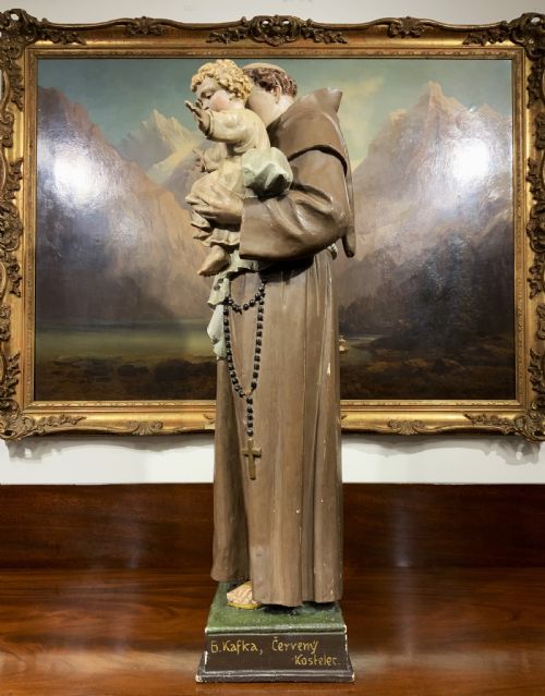 fig 5. A carved polychrome wood statue depicting a saint in a brown robe holding the infant Jesus.