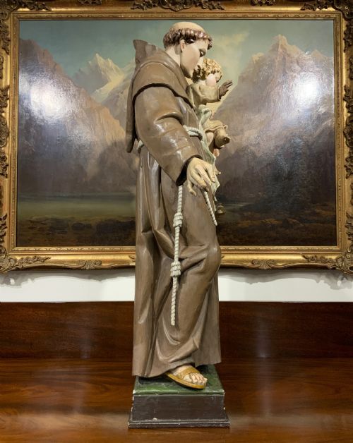 fig 8. A carved polychrome wood statue depicting a saint in a brown robe holding the infant Jesus.