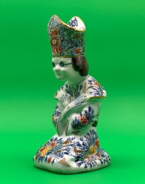 A LATE 18THC DUTCH DELFT POLYCHROME FAIENCE KNEELING BISHOP CANDLE STICK HOLDER