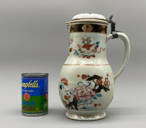fig 1. An 18th-century Chinese porcelain jug with hand-painted Famille Rose floral enamels, a metal-mounted lid, and a loop handle.