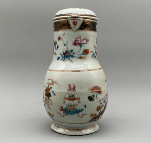 fig 2. An 18th-century Chinese porcelain jug with hand-painted Famille Rose floral enamels, a metal-mounted lid, and a loop handle.