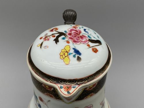 fig 6. An 18th-century Chinese porcelain jug with hand-painted Famille Rose floral enamels, a metal-mounted lid, and a loop handle.