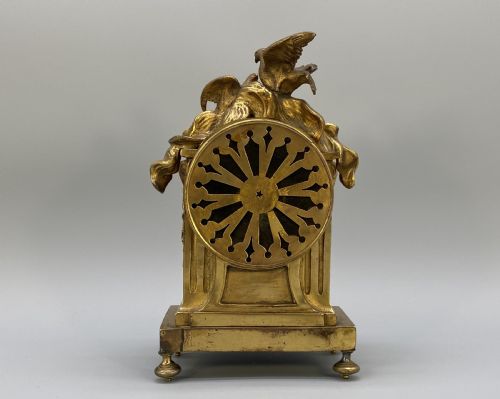 fig 4. An antique French gilt bronze mantel clock surmounted by two sculpted doves, featuring an ornate pedestal base and a white enamel dial with Roman numerals.