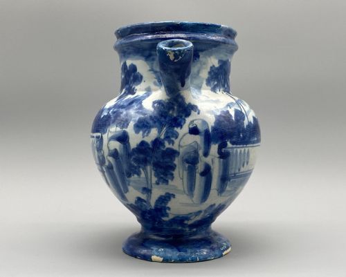 fig 5. An 18th-century Italian Savona majolica wet drug jar featuring hand-painted cobalt blue landscapes, a single side handle, a raised spout, and a pedestal base.