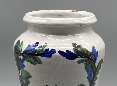 fig 6. A pair of white tin-glazed ceramic albarello apothecary jars featuring hand-painted green foliage wreaths and Latin script on pedestal bases.