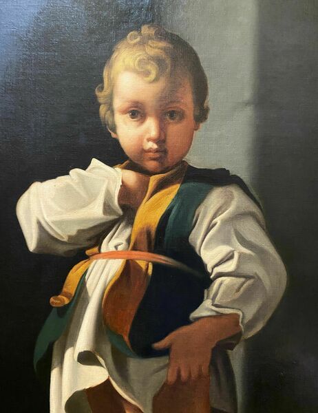 fig 3. An eighteenth-century Baroque style oil painting on canvas depicting a standing young child dressed in a white tunic and green vest, set within a carved gilt frame.