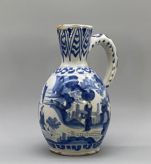 fig 2. A 17th-century Dutch Delftware ceramic jug featuring hand-painted blue chinoiserie scenes on an opaque white tin glaze with a curved handle.