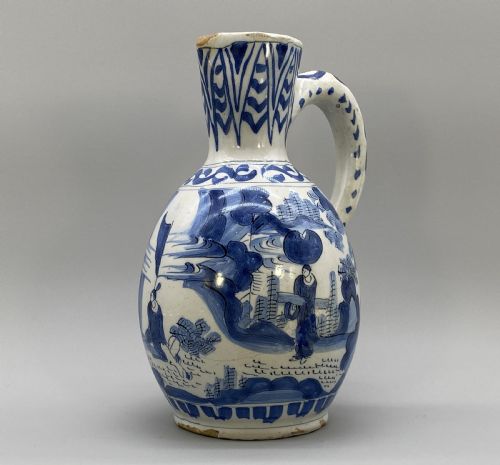 fig 3. A 17th-century Dutch Delftware ceramic jug featuring hand-painted blue chinoiserie scenes on an opaque white tin glaze with a curved handle.