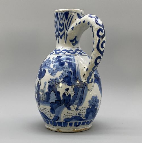 fig 4. A 17th-century Dutch Delftware ceramic jug featuring hand-painted blue chinoiserie scenes on an opaque white tin glaze with a curved handle.