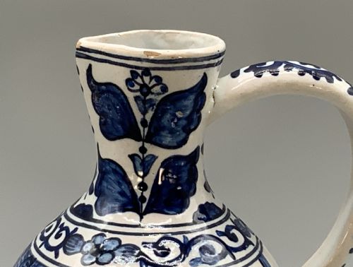 fig 4. An antique Dutch Delftware ceramic jug decorated with cobalt blue hand-painted Chinoiserie figures and botanical motifs against a white tin glaze.